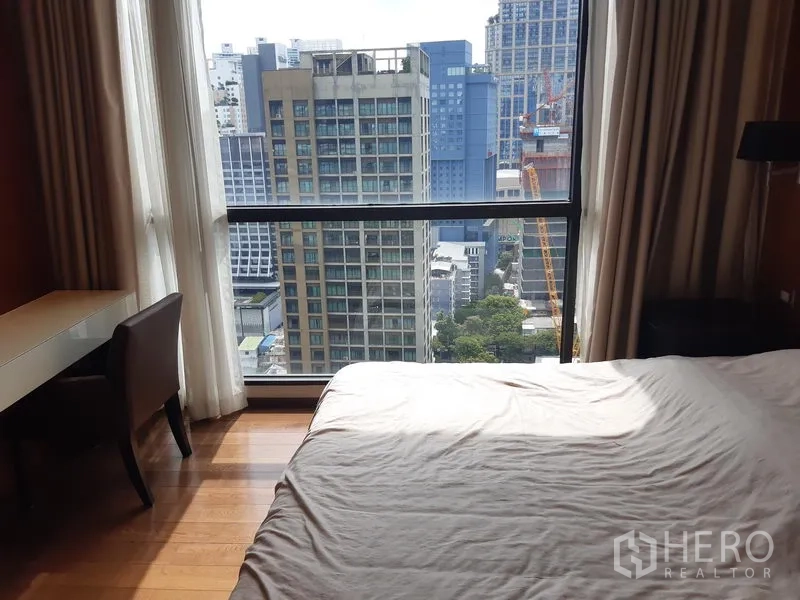 Condominium for rent in Khlong Toei, Bangkok - Master bedroom with wood floors, desk by the window and city view.