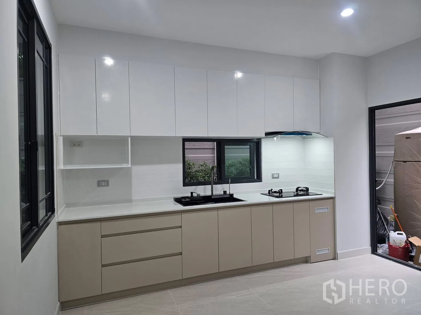 บ้านแฝด for rent in Suan Luang, Bangkok - ครัวบิวท์อินสไตล์โมเดิร์น ตู้สีขาว เตาแก๊ส และหน้าต่างรับแสง.