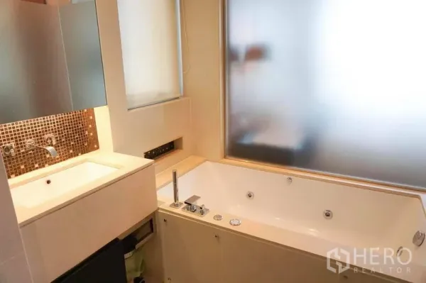 Condominium for rent in Khlong Toei, Bangkok - Modern Bangkok condo bathroom with large jetted bathtub, vanity and frosted window in Khlong Toei.