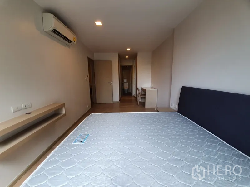 公寓 出租在Watthana, Bangkok - 卧室配空调与书桌，床垫已备，走廊通向浴室。