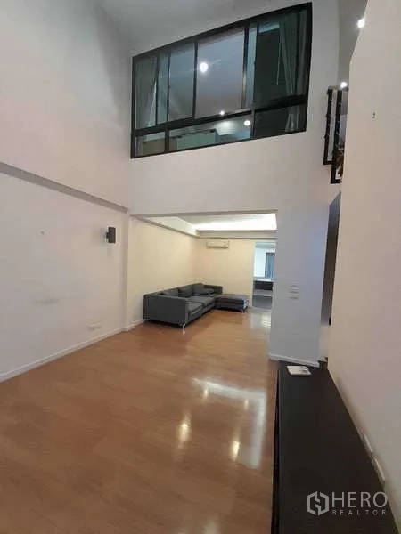 联排别墅 出租在Khlong Toei, Bangkok - 宽敞起居区，夹层玻璃墙与浅色木地