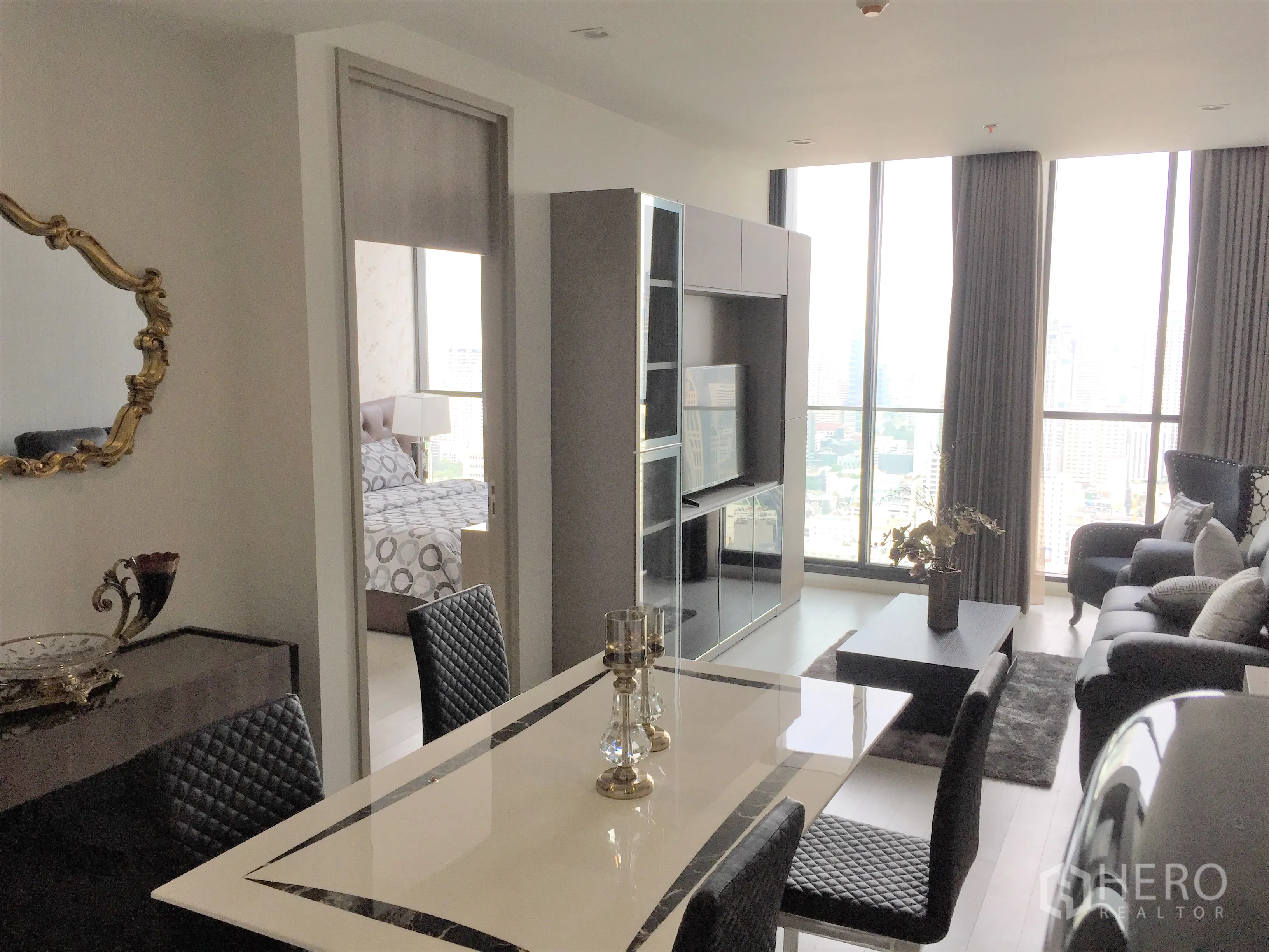 Condominium for rent in Pathum Wan, Bangkok - Open-plan living and dining area with tall windows and expansive city skyline views.