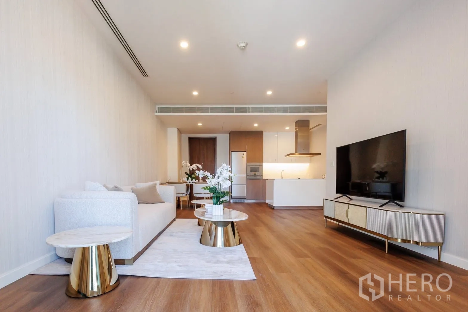 คอนโด for rent or sale in Pathum Wan, Bangkok - โถงนั่งเล่นเชื่อมครัวแบบเปิด ไฟดาวน์ไลท์ และโทนสีอบอุ่น