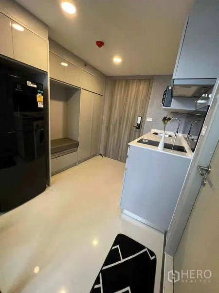 公寓 出售在Chatuchak, Bangkok - 入户走廊式厨房，通顶柜体、黑色冰箱与亮白地面。