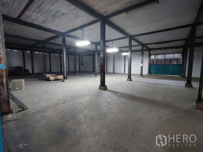 Warehouse for rent in Samut Sakhon - Open warehouse interior with steel columns and fluorescent lighting for storage or production.