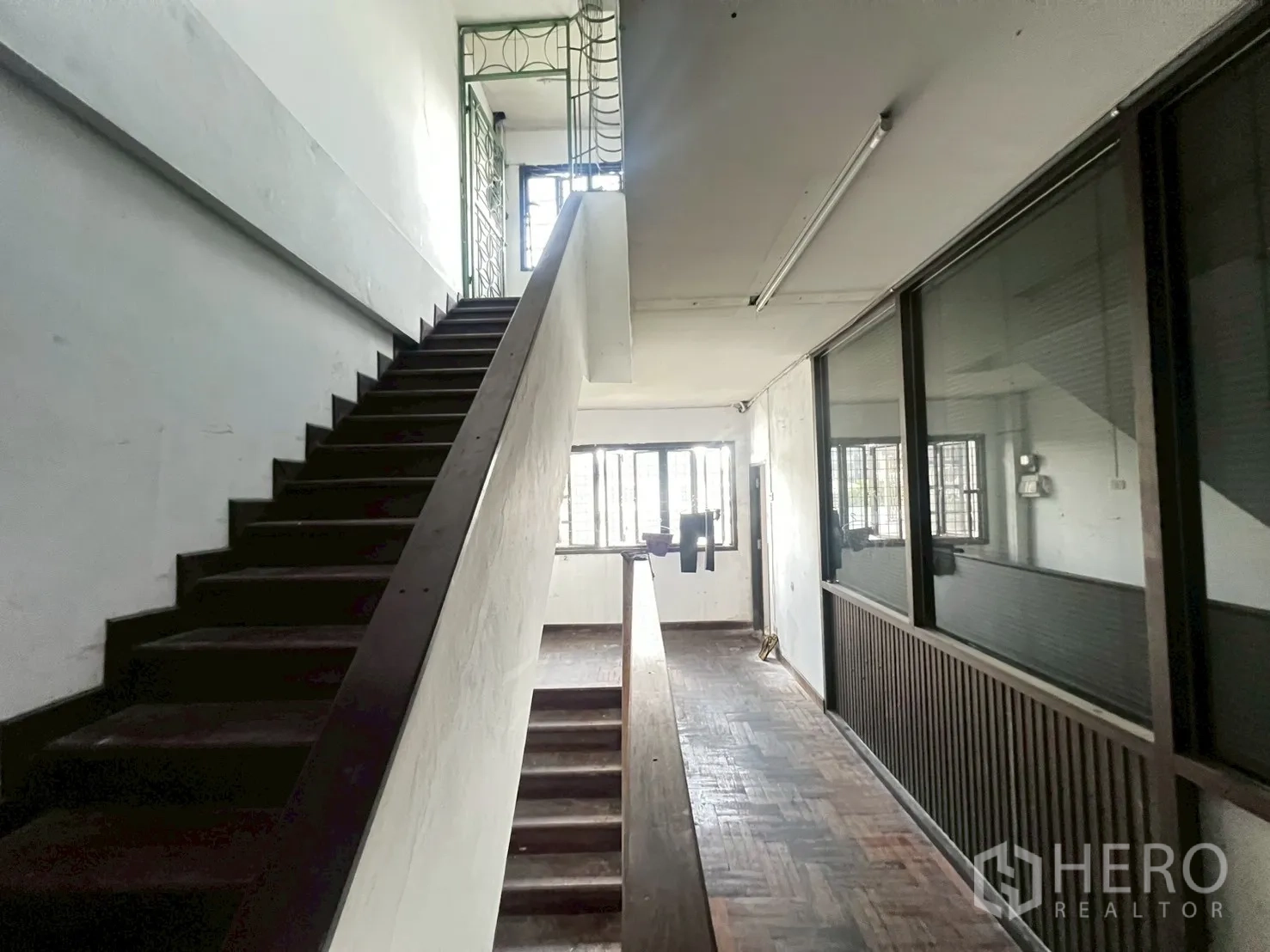 Shophouse for rent in Phra Khanong, Bangkok - Hallway with wooden stairs, parquet floor and full-height glass partition.
