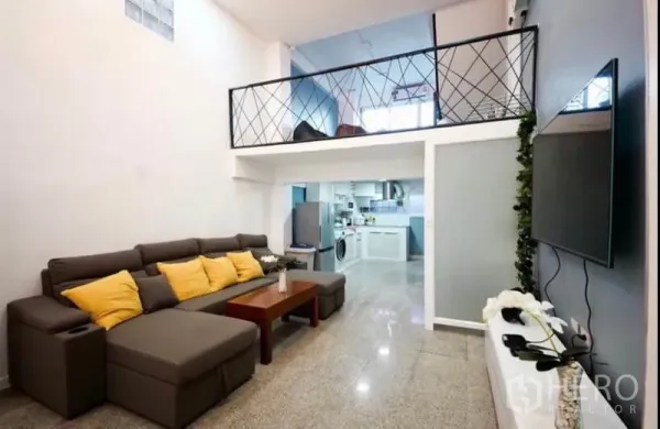 Townhouse for rent in Ratchathewi, Bangkok - Bright living room with sectional sofa, wall-mounted TV and mezzanine level above.