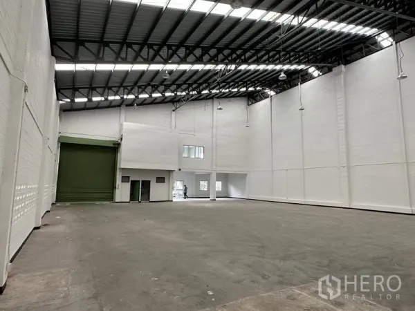 Factory for rent in Khlong Luang, Pathum Thani - Open factory floor with high-bay lighting, steel roof and rear office with loading dock access.