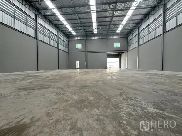 Factory for rent or sale in Bang Bo, Samut Prakan - High-clearance warehouse hall with steel roof and polished concrete floor, loading bay visible.