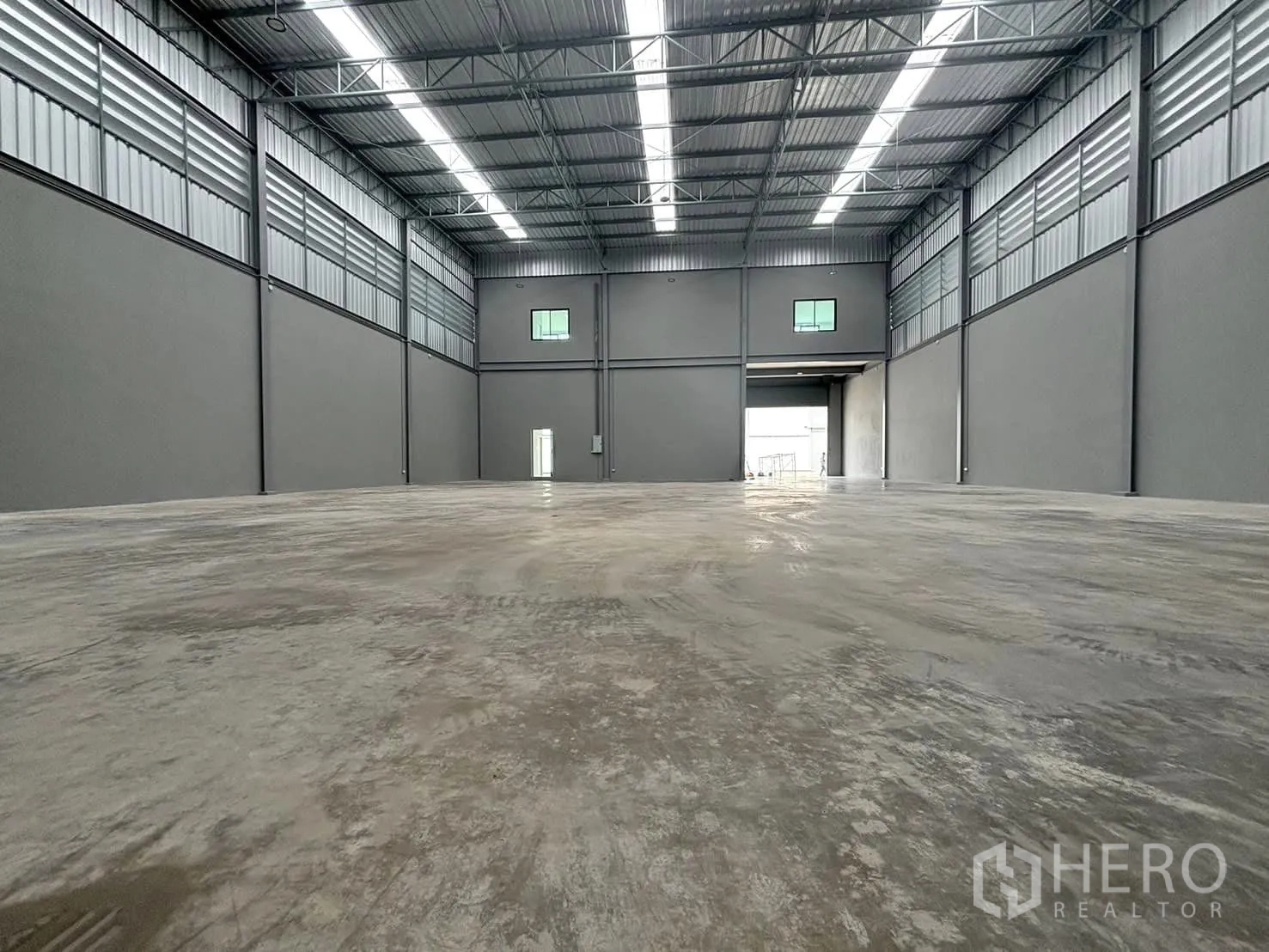 Factory for rent or sale in Bang Bo, Samut Prakan - High-clearance warehouse hall with steel roof and polished concrete floor, loading bay visible.