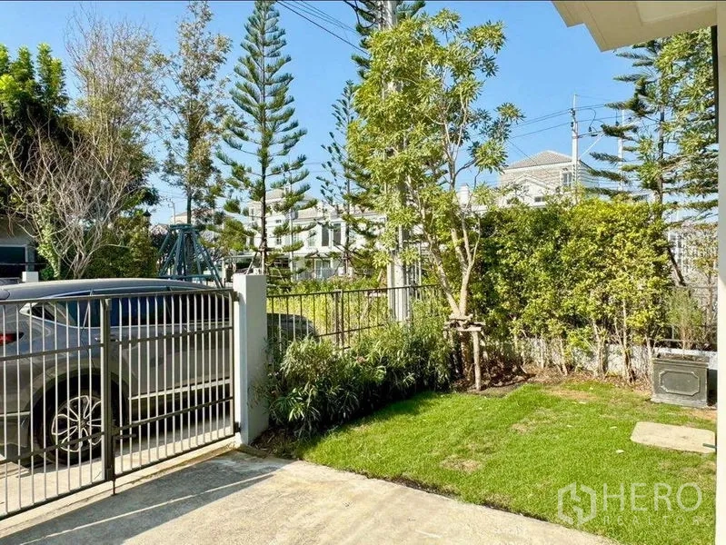 联排别墅 出租或出售在Prawet, Bangkok - 带大门的车道与草坪绿树，提供私密的室外空间。