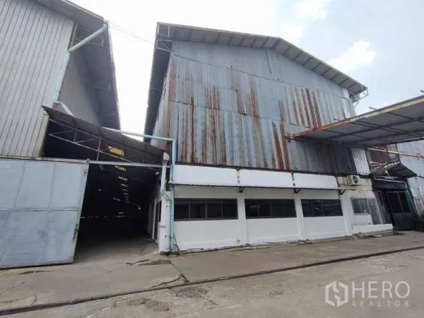 Warehouse for rent in Samut Sakhon - Exterior of corrugated metal warehouse with large sliding gate and canopy at entry.
