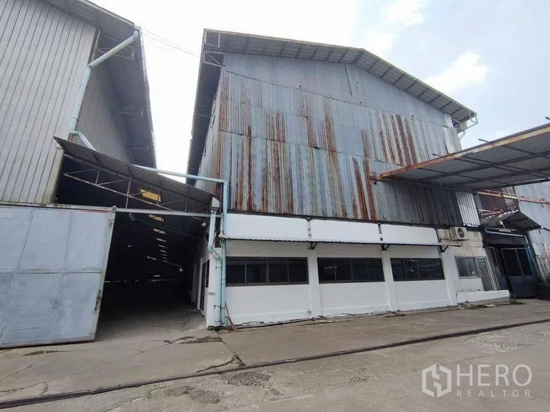 Warehouse for rent in Samut Sakhon - Exterior of corrugated metal warehouse with large sliding gate and canopy at entry.