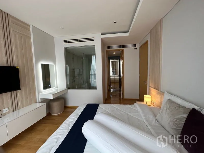 公寓 出租在Watthana, Bangkok - 温馨卧室带梳妆台、壁挂电视，与浴室之间为玻璃窗。