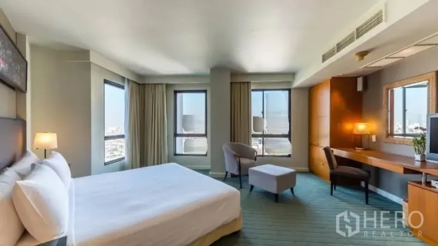 Condominium for rent in Bang Kho Laem, Bangkok - Corner bedroom featuring large windows, city views and a long built-in desk.