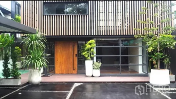 带办公室的家 出租或出售在Khlong Toei, Bangkok - 当代立面，竖向木格与大面积玻璃，入口两侧点缀绿植。