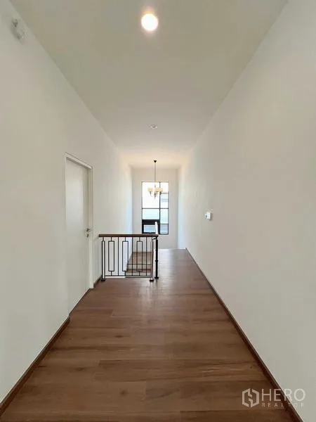 独立式住宅 出售在Bangkok Noi, Bangkok - 二层走廊明亮，木地板与黑色金属楼梯栏杆。