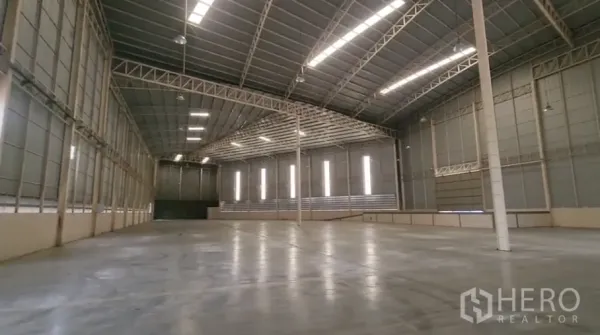 Warehouse for rent in Mueang Samut Sakhon, Samut Sakhon - Open warehouse bay showing long-span trusses, bright strip lighting, and unobstructed floor area.