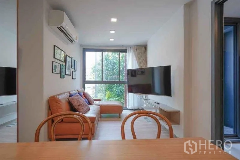 公寓 出租在Watthana, Bangkok - 客餐一体空间，墙面电视与园景视野。