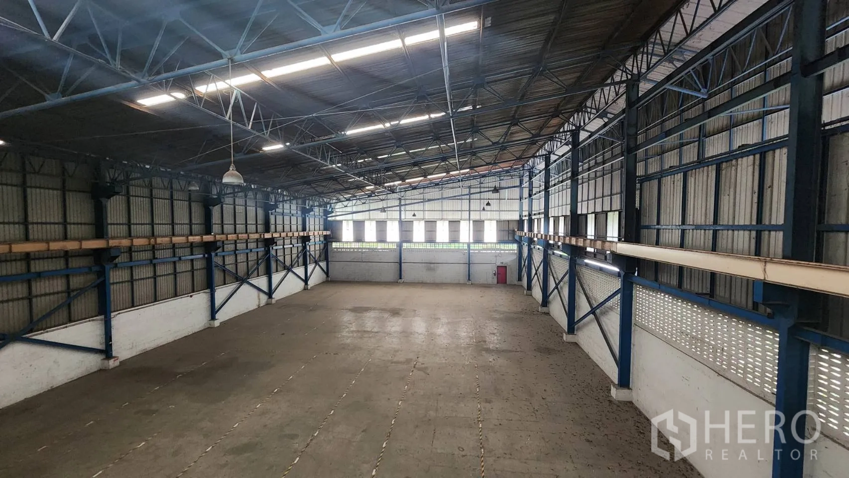 Warehouse for rent in Mueang Samut Prakan, Samut Prakan - High-angle view across the open warehouse floor with skylights and ventilation windows.