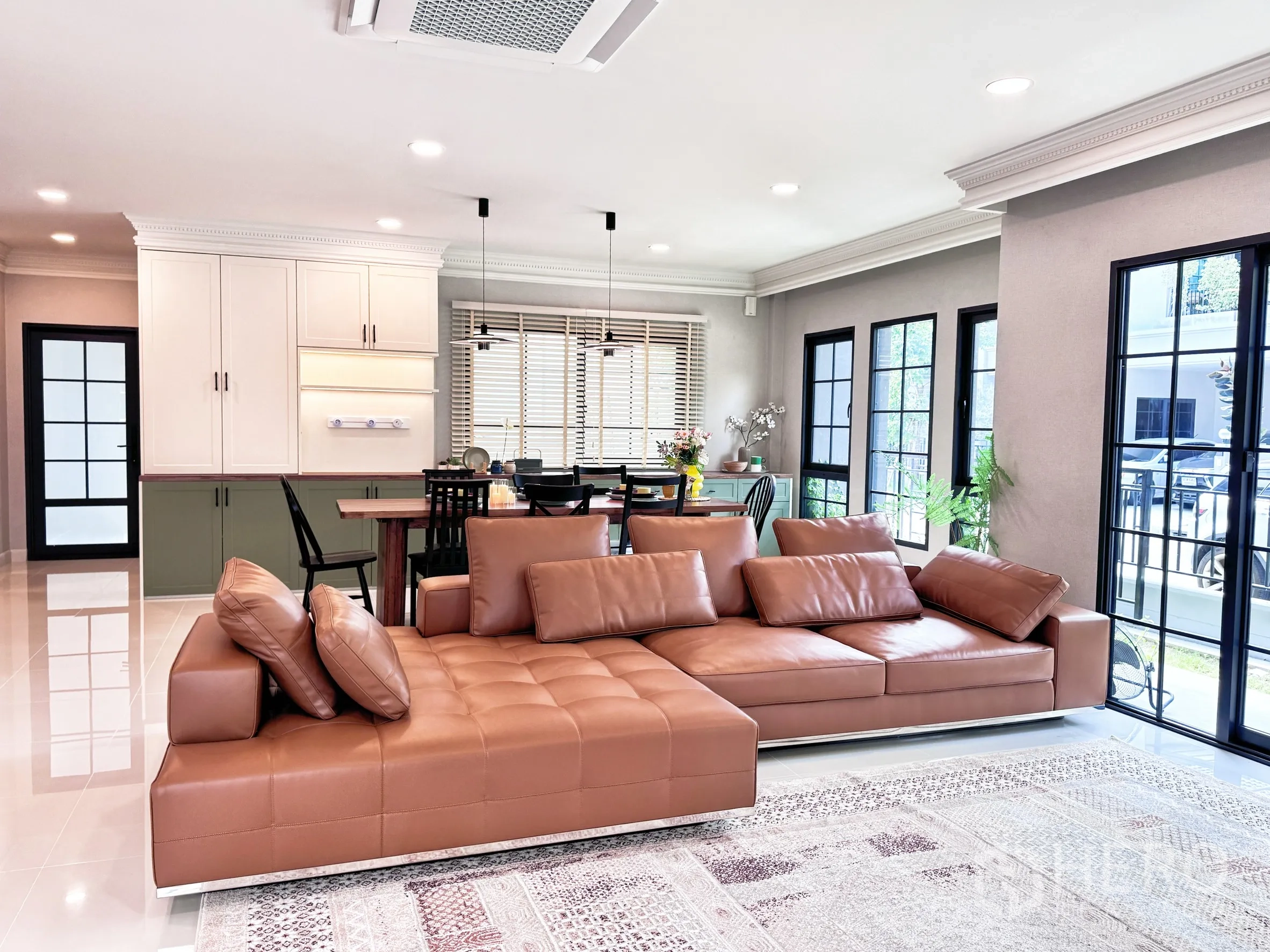บ้านเดี่ยว for rent in Bang Phli, Samut Prakan - ห้องนั่งเล่นแบบโอเพนสเปซสว่าง พร้อมโซฟาหนังสีน้ำตาล ชุดทานอาหาร และหน้าต่างบานใหญ่