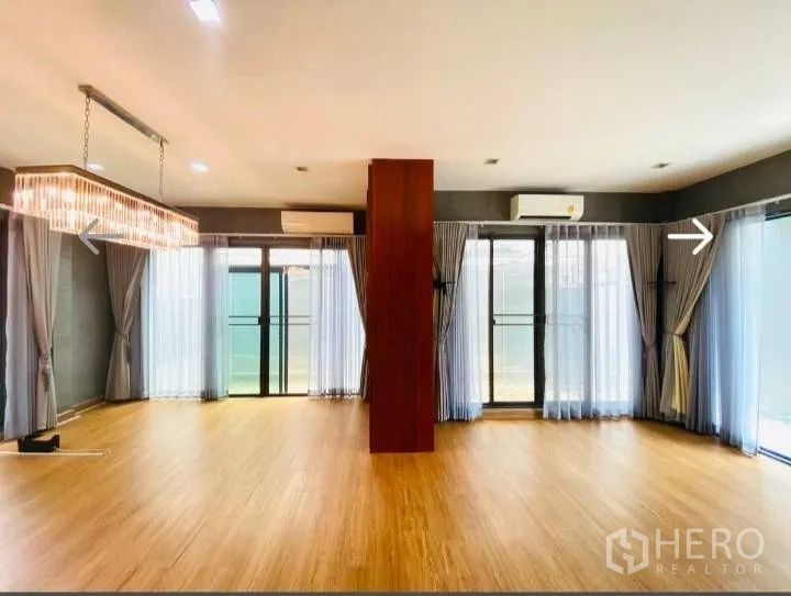 Detached House for sale in Saphan Sung, Bangkok - Open-plan living room with chandeliers, wood floors and multiple glass doors.