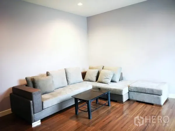 Townhouse for rent in Suan Luang, Bangkok - Upstairs family lounge with gray sectional sofa and warm wood flooring.
