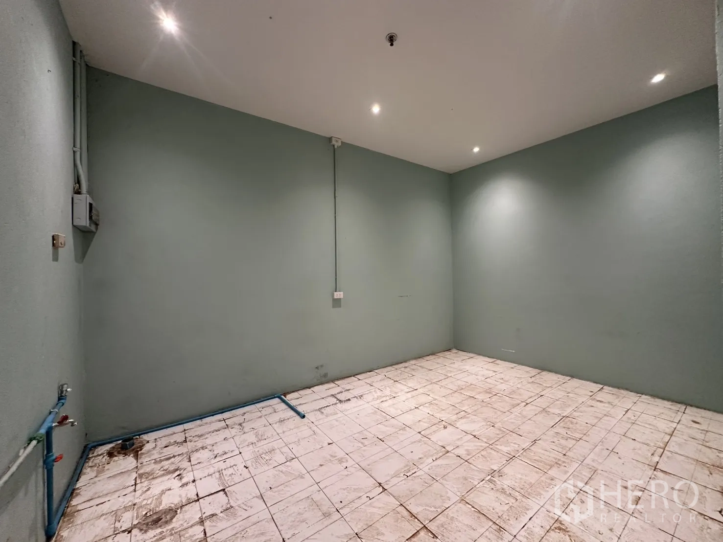 零售空间 for rent in Watthana, Bangkok - 服务区角度，绿色墙面、白色瓷砖地面，蓝色给水管与电箱。