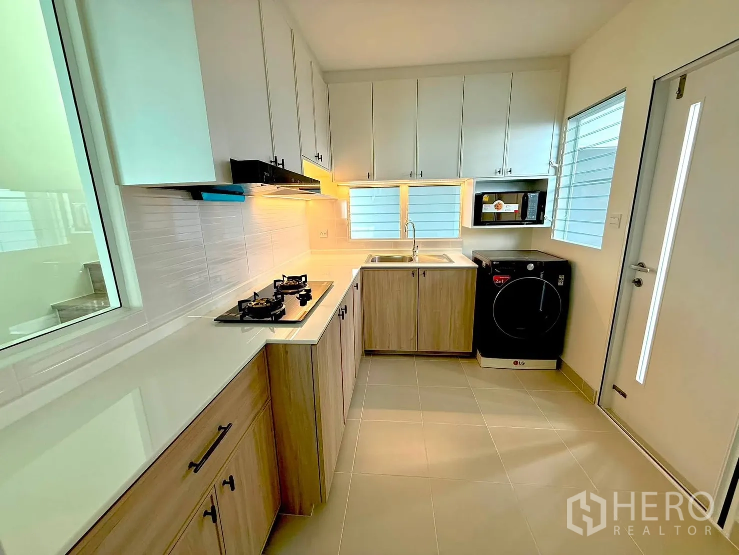 Detached House for rent in Bang Phli, Samut Prakan - Modern kitchen with gas hob, range hood, sink, cabinets, and window light.