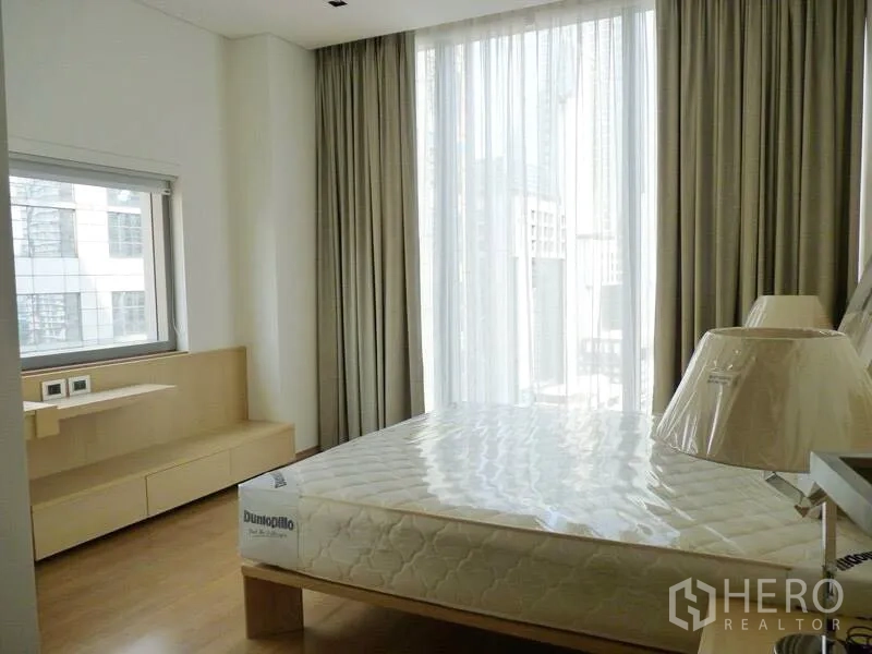 Condominium for rent in Bang Rak, Bangkok - Second bedroom with big window, sheer curtains and light wood built-ins overlooking the city.