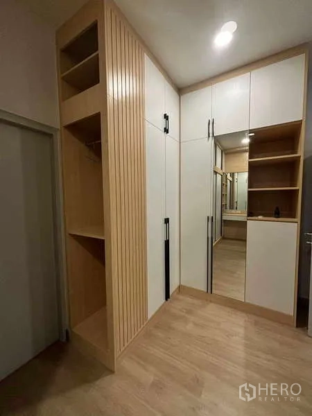 独立式住宅 出租在Mueang Nonthaburi, Nonthaburi - 转角衣帽柜，木格栅与带镜柜体的更衣区。