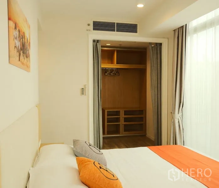 Condominium for rent in Bang Rak, Bangkok - Master bedroom leading to curtained walk-in closet with built-in storage.