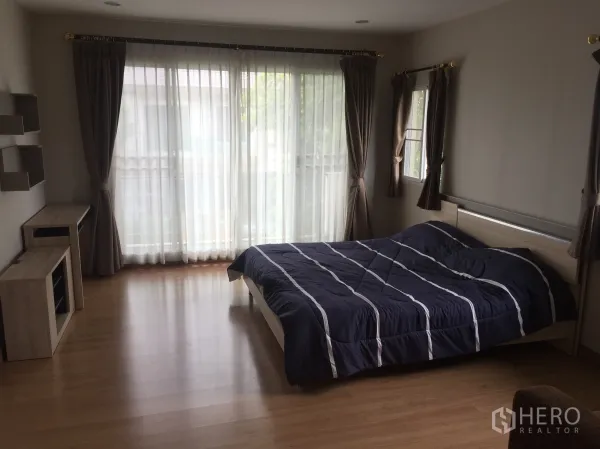 独立式住宅 出租在Pathum Thani - 宽敞主卧，木地板，推拉落地门通往阳台，摆放双人床。