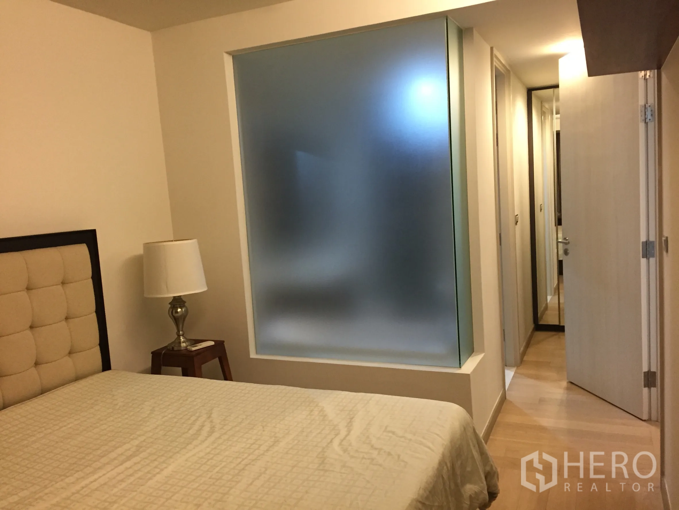 Condominium for rent or sale in Watthana, Bangkok - Bedroom corridor featuring a frosted glass panel, mirrored wardrobe, and light wood flooring.