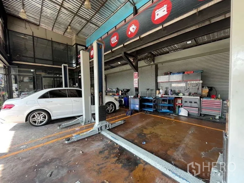 Warehouse for rent in Lat Phrao, Bangkok - Vehicle service bay featuring car‑lift columns, marked lanes and tool cabinets inside the warehouse.