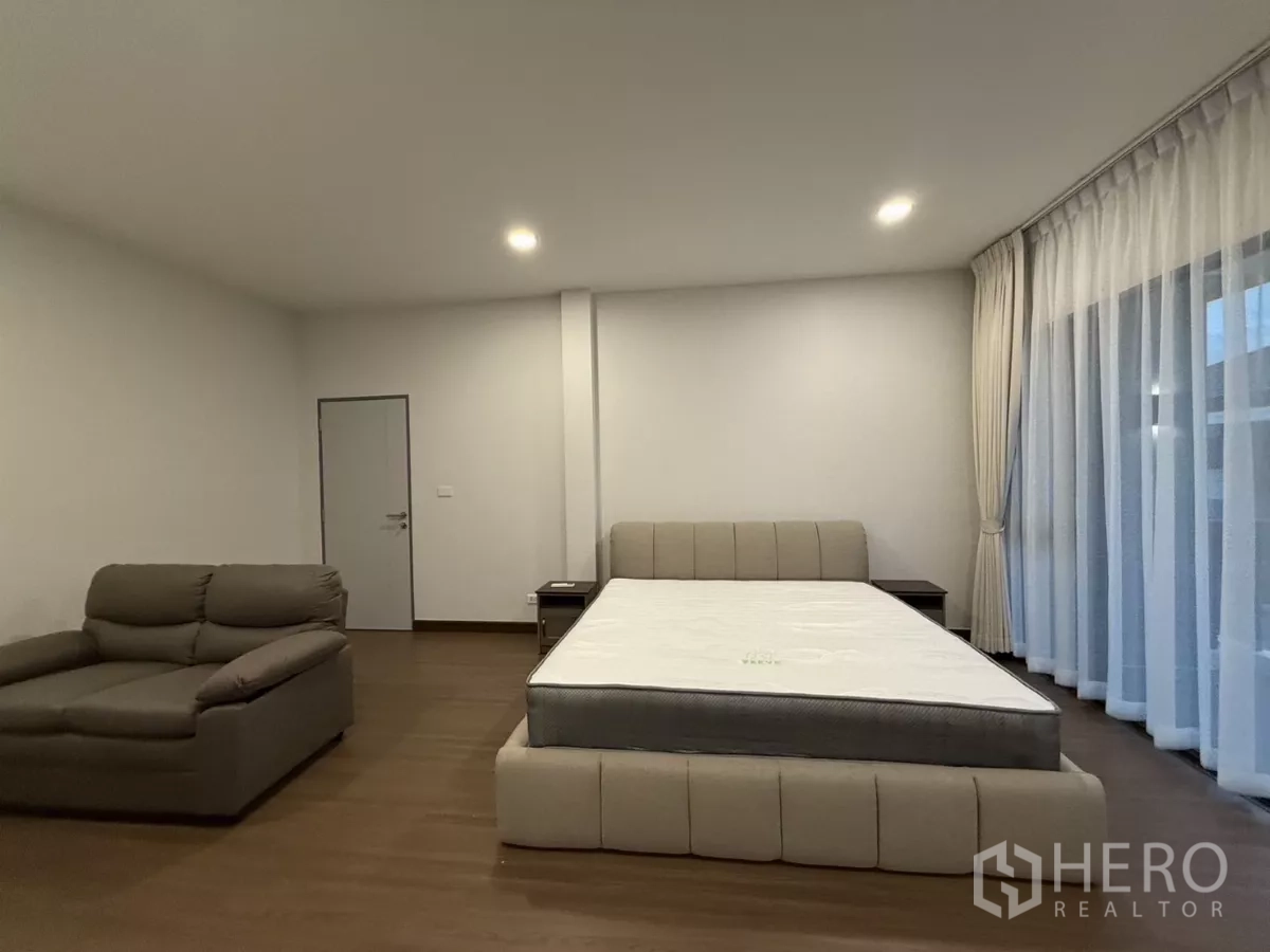 独立式住宅 出租在Bang Phli, Samut Prakan - 宽敞卧室，特大床、沙发与木地板。