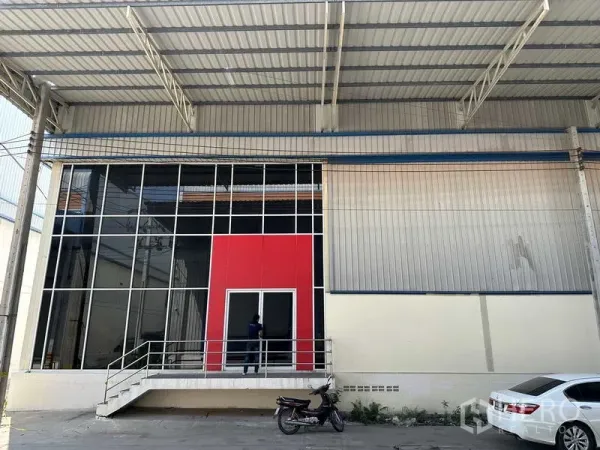 工厂 出租在Bang Phli, Samut Prakan - 带红色装饰面与台阶的玻璃门入口，位于大型金属雨棚下。
