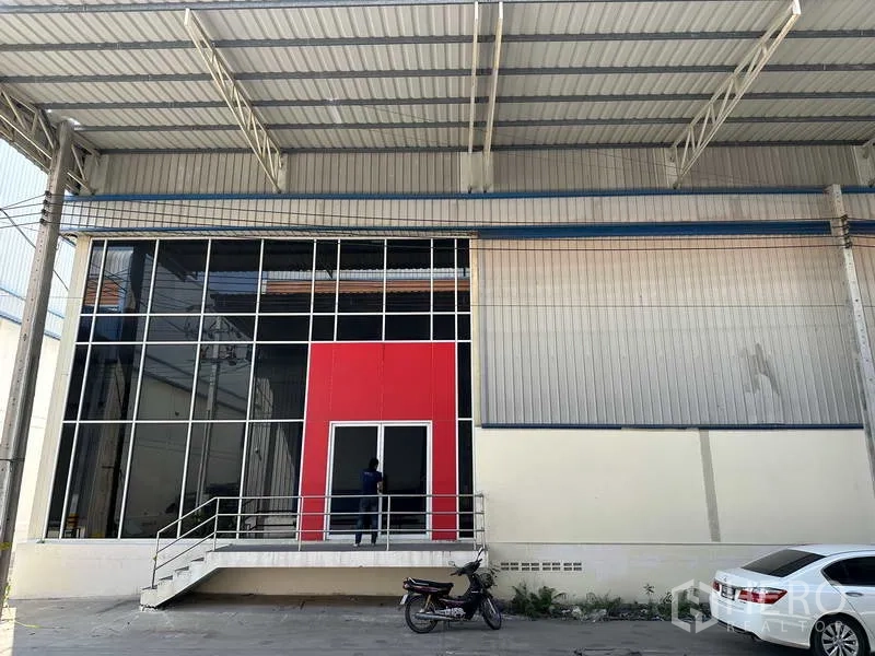 工厂 出租在Bang Phli, Samut Prakan - 带红色装饰面与台阶的玻璃门入口，位于大型金属雨棚下。