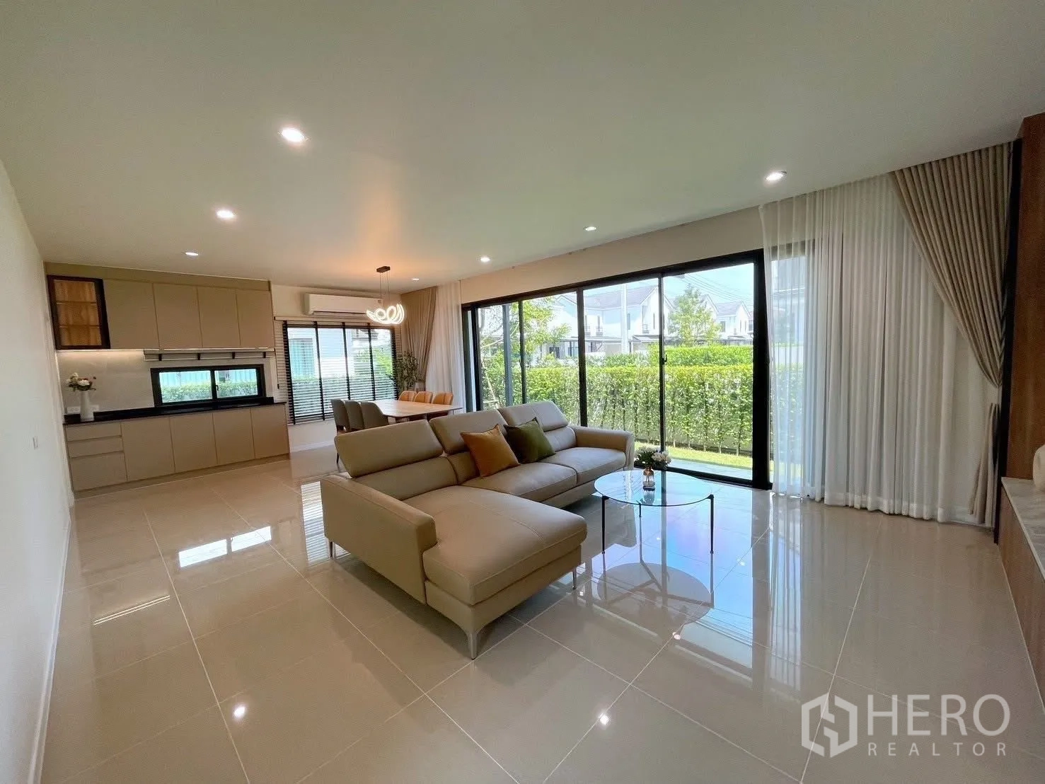 บ้านเดี่ยว for rent in Bang Phli, Samut Prakan - พื้นที่นั่งเล่น–ทานอาหารสว่าง เปิดสู่สนามหญ้าหน้าบ้านผ่านประตูกระจกบานเลื่อนและรั้วพุ่ม