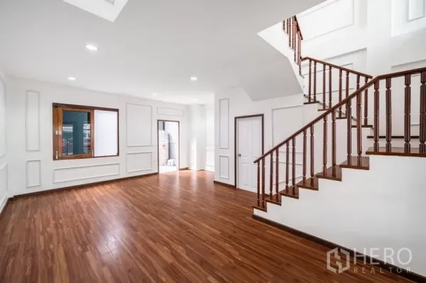 Townhouse for sale - Spacious ground-floor living room with recessed lights and a wooden staircase.