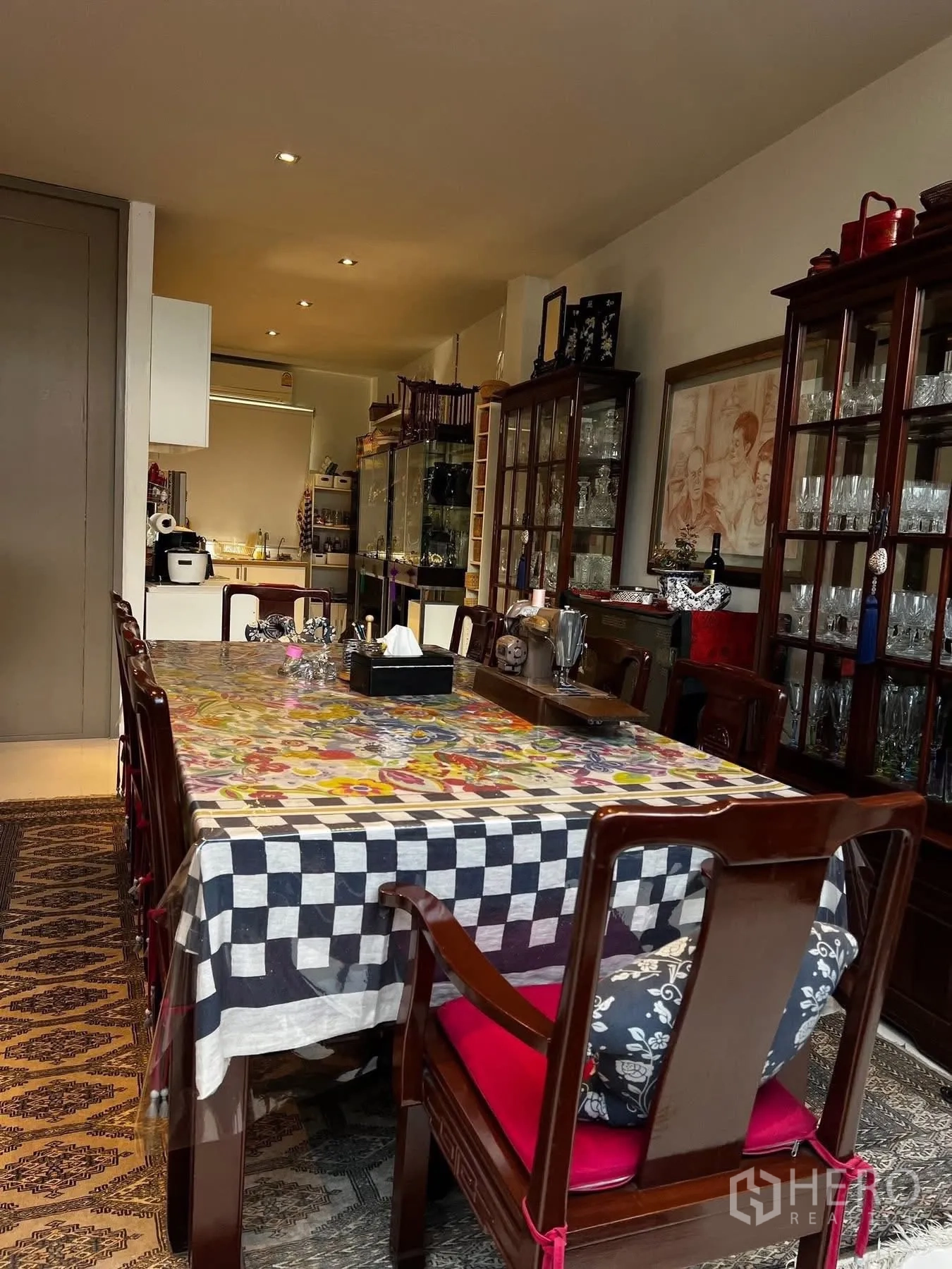 联排别墅 for rent or sale in Watthana, Bangkok - 餐区设长桌与木椅，通向厨房的玻璃柜陈列区。