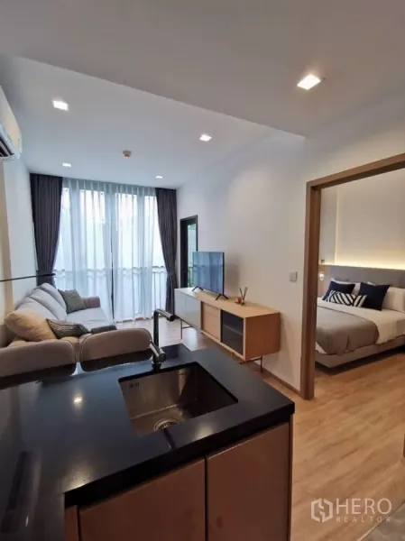 公寓 出租在Watthana, Bangkok - 开放式客厅配沙发与电视柜，可见独立卧室。