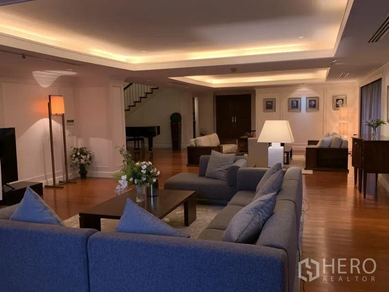 公寓 出租或出售在Watthana, Bangkok - 宽阔起居区，灰色转角沙发与氛围灯，木地板。