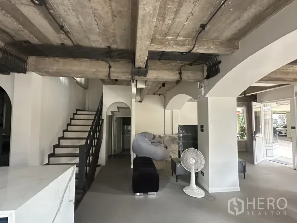 พื้นที่ขายของ for rent in Watthana, Bangkok - พื้นที่ชั้นล่างเห็นบันได เสาโค้ง และเพดานคอนกรีตเปลือย.