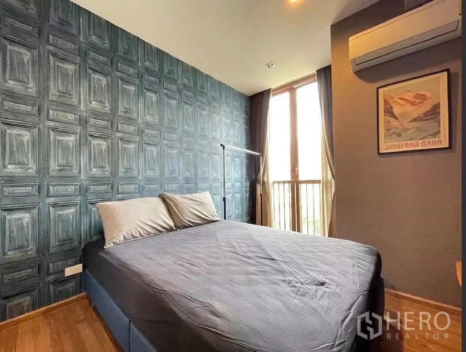 Condominium for rent in Watthana, Bangkok - Bedroom with double bed, patterned feature wall, air conditioner, and tall window.