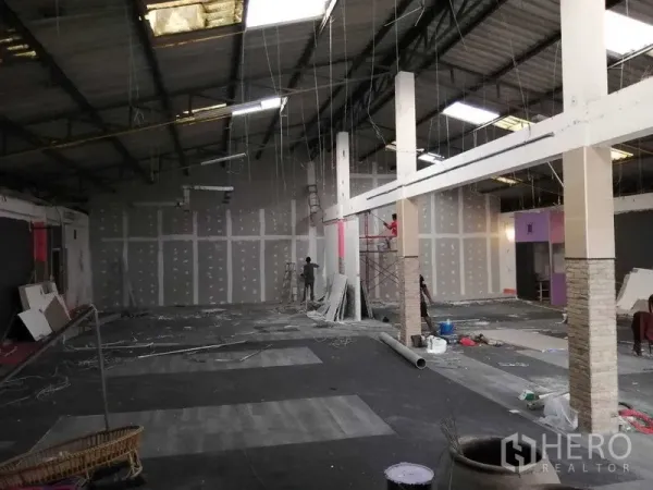 Warehouse for rent in Nonthaburi - Expansive warehouse hall under renovation with high ceilings, columns, drywall partitions and scaffolding.