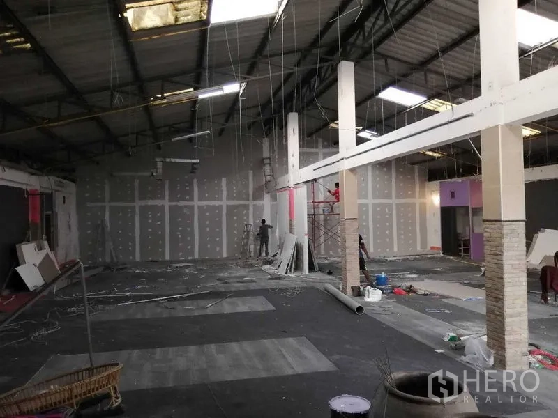 Warehouse for rent in Nonthaburi - Expansive warehouse hall under renovation with high ceilings, columns, drywall partitions and scaffolding.