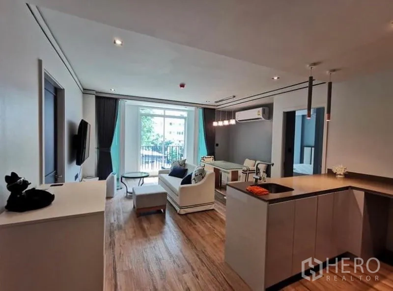 Condominium for rent in Sathon, Bangkok - Open-plan living and dining area with balcony view, wood floors and a modern kitchen island.