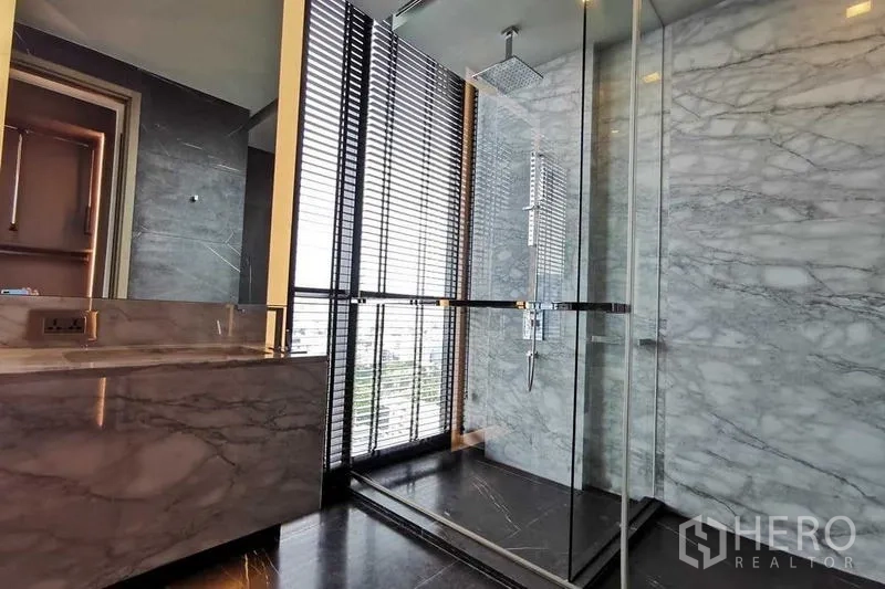 Condominium for rent or sale in Watthana, Bangkok - Marble bathroom with glass shower enclosure and rainfall shower.
