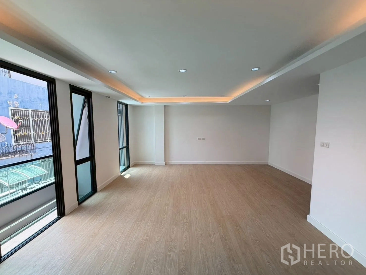 Townhouse for sale in Phra Khanong, Bangkok - Spacious multipurpose room with large windows and cove lighting.